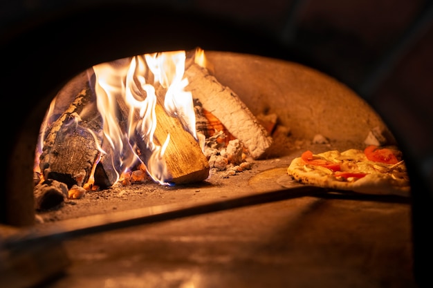 Bezpłatne zdjęcie pieczenie pysznej pizzy w piecu opalanym drewnem