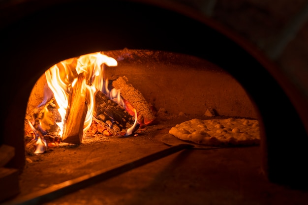 Bezpłatne zdjęcie pieczenie pysznej pizzy w piecu opalanym drewnem