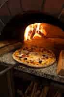 Bezpłatne zdjęcie pieczenie pysznej pizzy w piecu opalanym drewnem