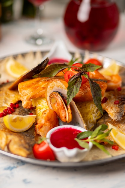 Pieczona ryba z grilla i owoce morza podawane z ziołami, cytryną i czerwonym sosem pomidorowym.