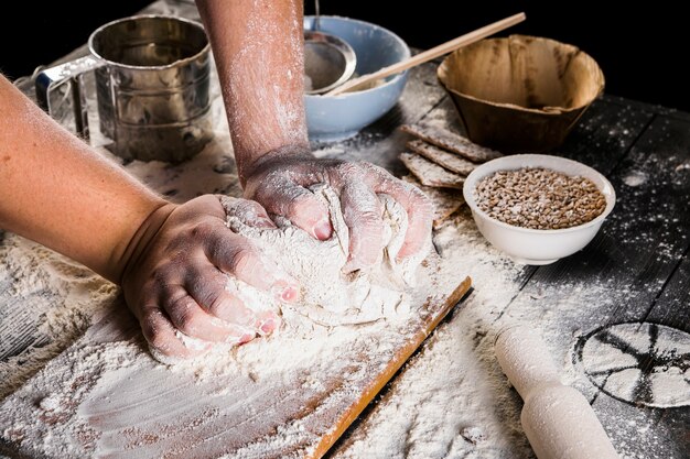 Piekarz ugniata ciasto z mąką nad kuchennym stołem