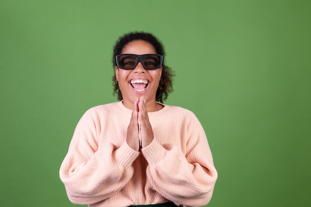 Piękna afroamerykańska kobieta na zielonej ścianie z okularami kinowymi 3d szczęśliwa wesoła pozytywna