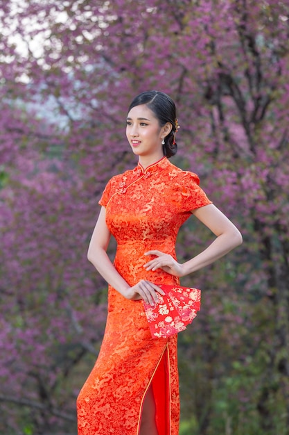 Bezpłatne zdjęcie piękna azjatka pokazuje coś i bierze czerwone koperty w chiński nowy rok
