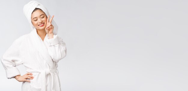 Piękna azjatycka kobieta pokazująca znak pokoju lub dwa palce z szczęśliwym uczuciem na białym tle na białym tle