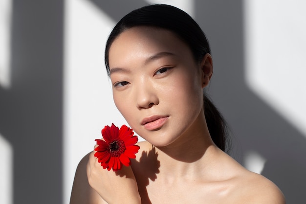 Piękna azjatycka kobieta pozuje trzymając różę z idealną skórą