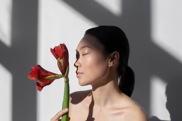 Bezpłatne zdjęcie piękna azjatycka kobieta pozuje trzymając różę z idealną skórą