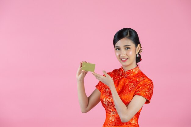 Piękna Azjatycka kobieta szczęśliwy uśmiech i pokaż kartę kredytową w chińskim nowym roku na różowym tle.