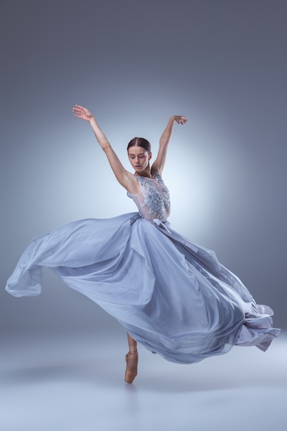 Piękna baletnica tańczy w długiej liliowej sukience na liliowym tle