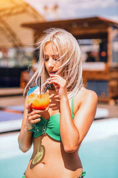 Piękna blondynka młoda seksowna kobieta w zielonym bikini, ciesząc się basenem w pobliżu plaży