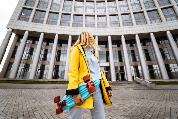 Bezpłatne zdjęcie piękna blondynki kobieta pozuje z deskorolka