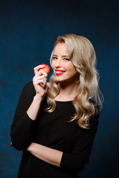 Piękna blondynki kobieta w czerni sukni mienia jabłku
