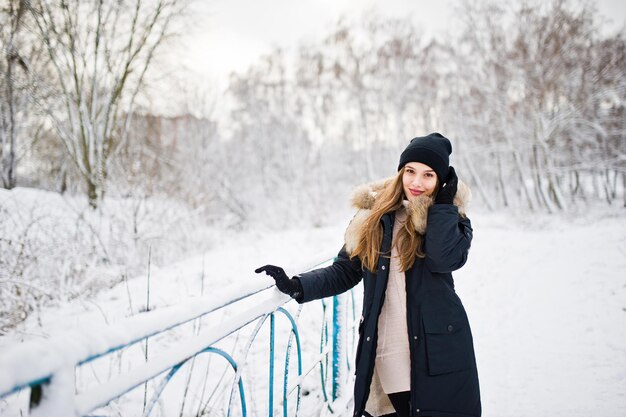 Piękna brunetka dziewczyna w zimowej ciepłej odzieży Model na zimowej kurtce i czarnym kapeluszu