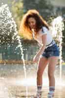Bezpłatne zdjęcie piękna dziewczyna, ciesząc się jej dniem, bawiąc się wodą