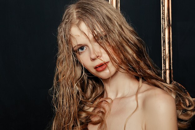 Piękna dziewczyna moda model naturalny makijaż mokre włosy na czarnym tle złota w ciepłych kolorach. portret młodej kobiety z makijażem mody