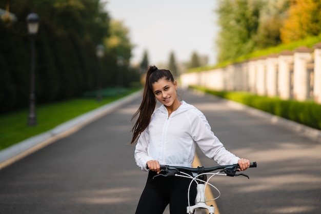 Piękna dziewczyna pozuje na białym rowerze. Spaceruj na łonie natury. Zdrowy tryb życia.