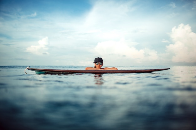Piękna dziewczyna pozuje siedzieć na desce surfingowej w oceanie