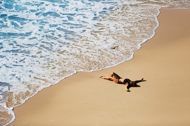 Piękna dziewczyna relaks na dzikiej plaży. niesamowity widok z góry.