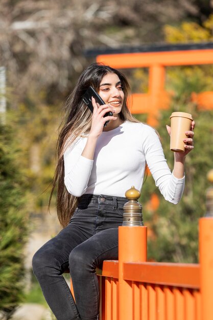 Piękna dziewczyna siedzi na ulicy i rozmawia przez telefon Wysokiej jakości zdjęcie