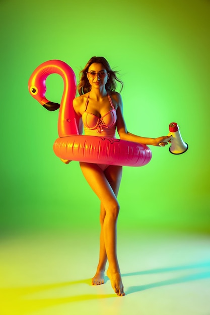Bezpłatne zdjęcie piękna dziewczyna w modnym stroju kąpielowym na gradientowym studio w neonowym świetle