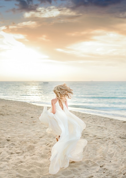 Piękna elegancka dziewczyna pozuje w świetle słonecznym na plaży