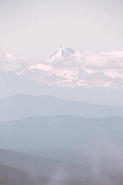 Piękna góra pokryta śniegiem i otoczona chmurami podczas mglistej pogody