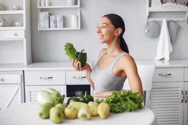 Piękna i sportowa kobieta w kuchni z warzywami