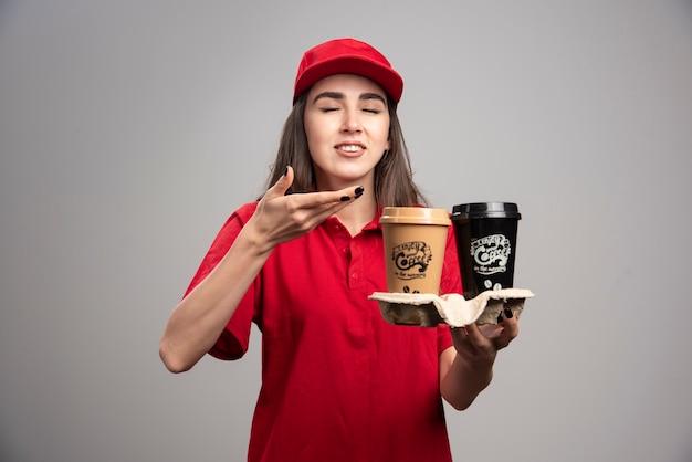 Piękna kobieta dostawy w czerwonym mundurze pachnie aromatem kawy.