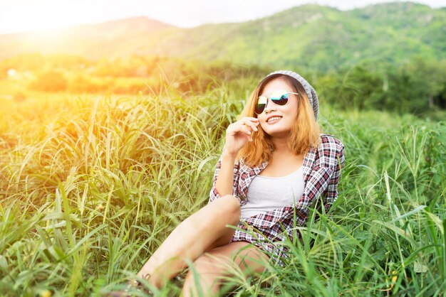 Piękna kobieta hipster siedzi na łące z naturą i moun