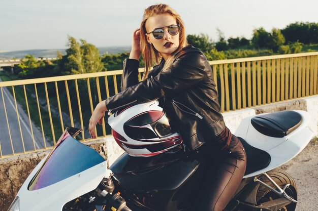 Piękna kobieta jedzie na motocyklu z okularami przeciwsłonecznymi