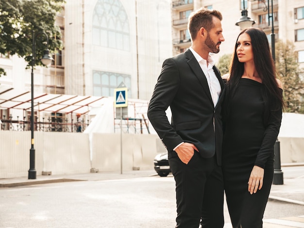 Piękna kobieta moda i jej przystojny elegancki chłopak w garniturze Seksowna brunetka modelka w czarnej sukni wieczorowej Modna para pozuje na ulicy w Europie Brutalny mężczyzna i jego kobieta na zewnątrz