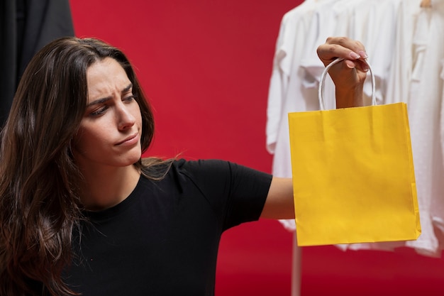 Piękna kobieta patrzeje żółtego torba na zakupy