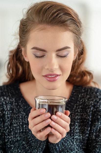 Bezpłatne zdjęcie piękna kobieta pije kawę i smakuje. dość młoda dziewczyna dorosłych relaks przy filiżance herbaty.