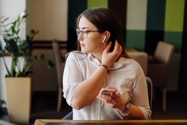 Piękna kobieta pracuje na swoim laptopie i telefonie w stylowej restauracji miejskiej