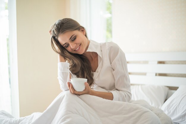Piękna kobieta przy jej sypialnią pije kawę w ranku