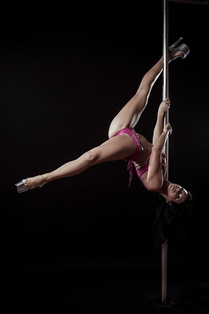 Piękna kobieta robi akrobatyczne i elastyczne sztuczki na słupie w studio tańca