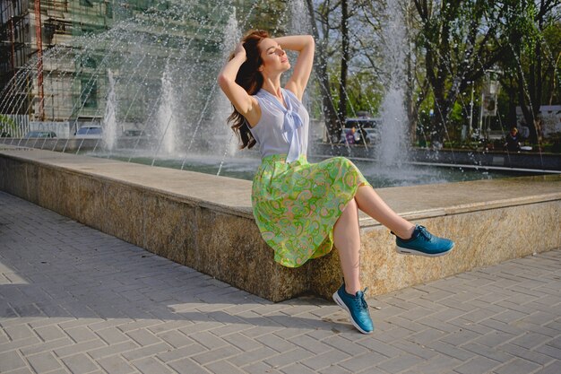 Piękna kobieta siedzi blisko fontanny