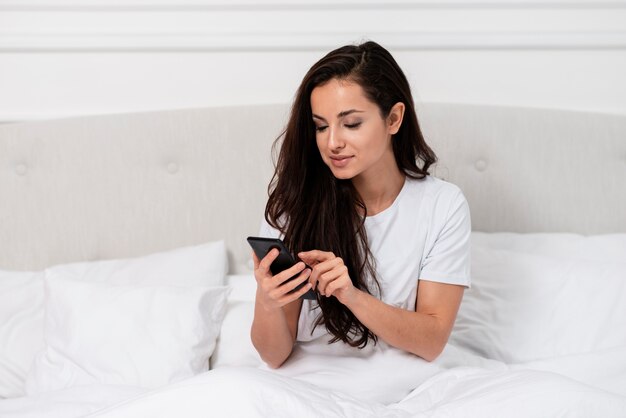 Piękna kobieta sprawdza jej telefon po budzić się up