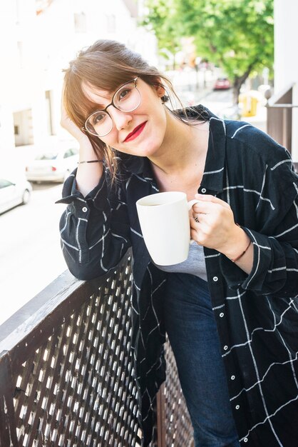 Piękna kobieta trzyma filiżankę kawy w eyeglasses