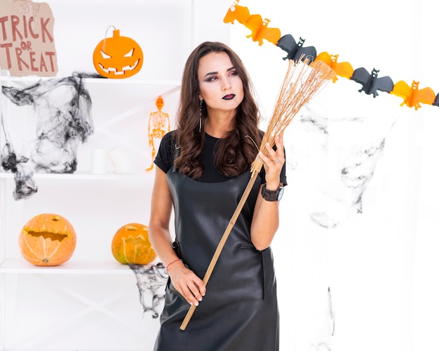 Bezpłatne zdjęcie piękna kobieta trzyma halloween miotłę