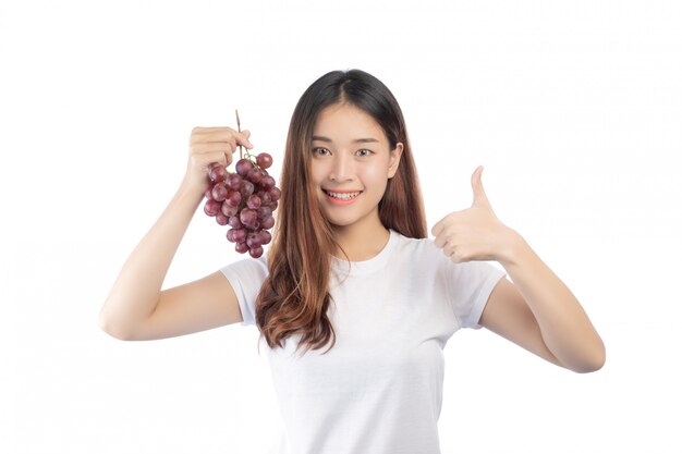 Piękna kobieta trzyma ręka winogrona z szczęśliwym uśmiechem, odizolowywającym na białym tle.