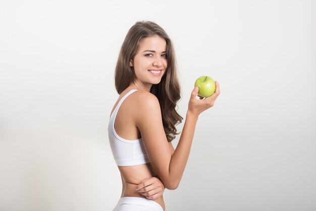 Piękna kobieta trzyma zielone jabłko, podczas gdy na białym tle