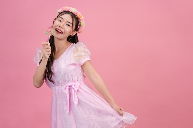 Piękna kobieta ubrana w różową księżniczkę bawi się swoim słodkim cukierek na różu.