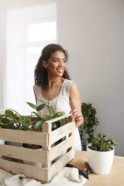 Bezpłatne zdjęcie piękna kobieta uśmiecha się pracy z roślinami w polu w miejscu pracy biała ściana.