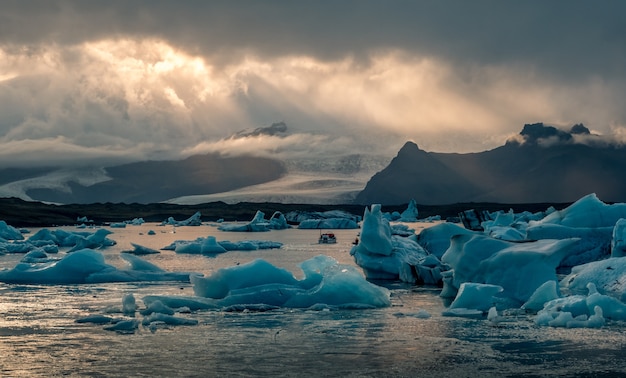 Piękna laguna Jokulsarlon na Islandii, z promieniami słońca z ciemnego, zachmurzonego nieba