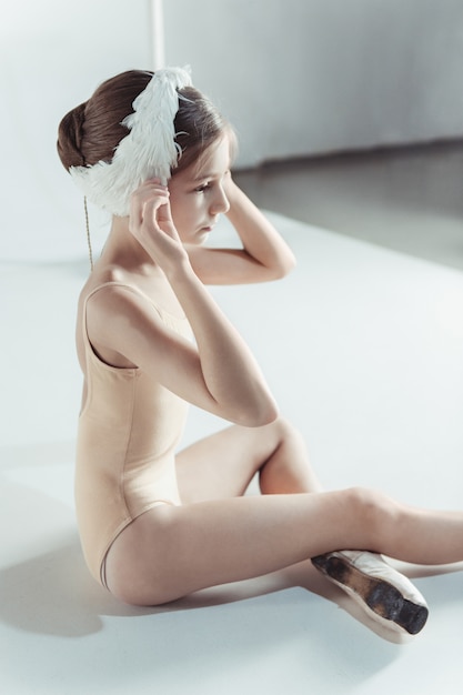 Bezpłatne zdjęcie piękna mała baletnica ubrana w biały łabędzi bandaż na głowie