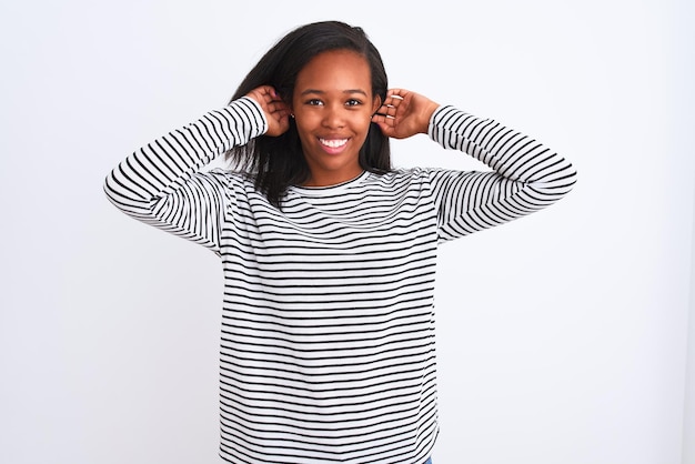 Bezpłatne zdjęcie piękna młoda afroamerykanka ubrana w zimowy sweter na odizolowanym tle uśmiechnięta ciągnąca uszy palcami zabawny gest problem z przesłuchaniem
