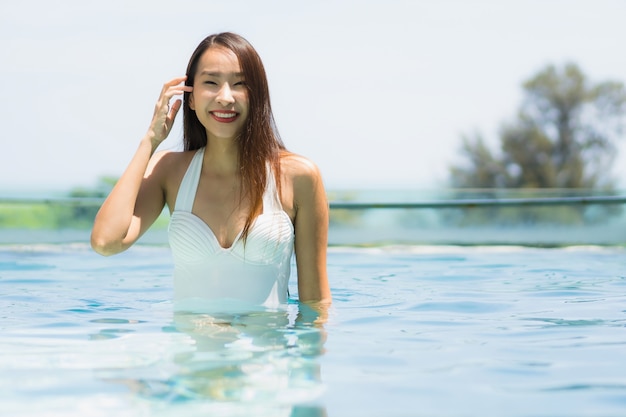 Piękna młoda azjatykcia kobieta szczęśliwa i uśmiech w pływackim basenie dla relaksujemy podróż i wakacje