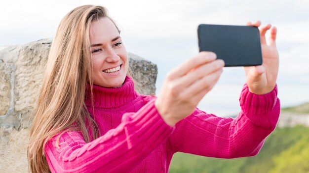 Piękna młoda kobieta bierze selfie outdoors
