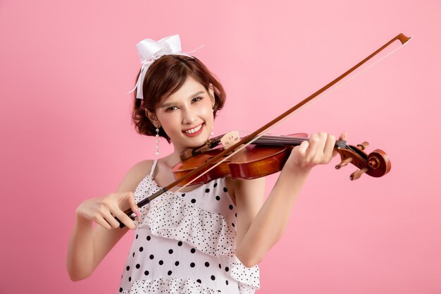 Piękna młoda kobieta gra skrzypce na różowo