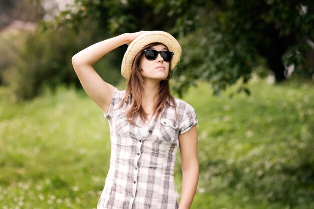 Piękna młoda kobieta nosi kapelusz fedora i okulary przeciwsłoneczne
